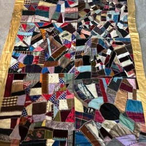 Antique silk crazy quilt. Simple red backing, intricate stitching. Small imperfe